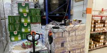 två lyfthanordningar med staplar av paketvaror i en lagerhall