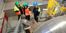 Tre män står vid en trappa i en pappersmassafabrik