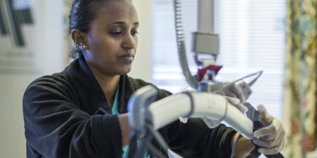 Person hanterar medicinsk utrustning i ett vårdrum.