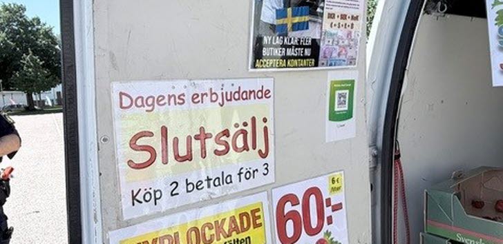 En skåpbil med skyltar som annonserar erbjudanden för svenska jordgubbar och information om priser.