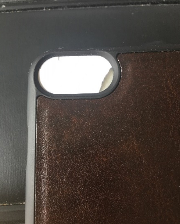 Bild som visar delar av bakstycket på en iPhone och en liten papperslapp som ska placeras över kamerans lins.