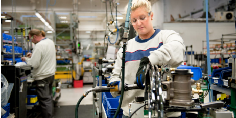 En person arbetar vid en stationär maskin i en fabrik.