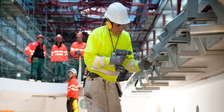 En byggarbetare på en byggarbetsplats arbetar med en skruvdragare.