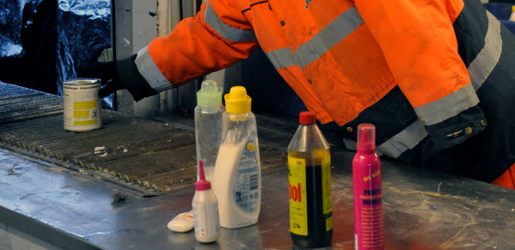 Person i varselkläder hanterar avfall som till exempel målarfärg och sprayflaskor