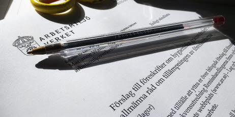Bild på sax, penna, häftapparat liggandes på ett dokument