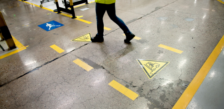 a worker walks on a marked path on the factory floor