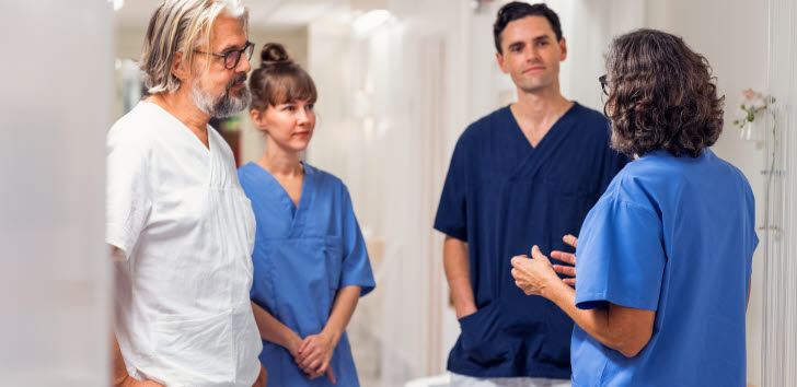 En grupp vårdpersonal står och pratar i en sjukhudkorridor