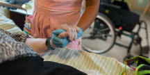 foto på omsorgspersonalens händer som håller i en äldres hand.