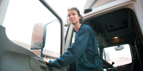 En kvinna som står i dörren till förarsätet på en lastbil.