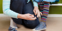 Bild på en person som knyter ett barns skor.