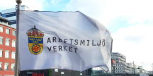 Bild på Arbetsmiljöverkets flagga vajandes i vinden i vad som tycks vara styv kuling.