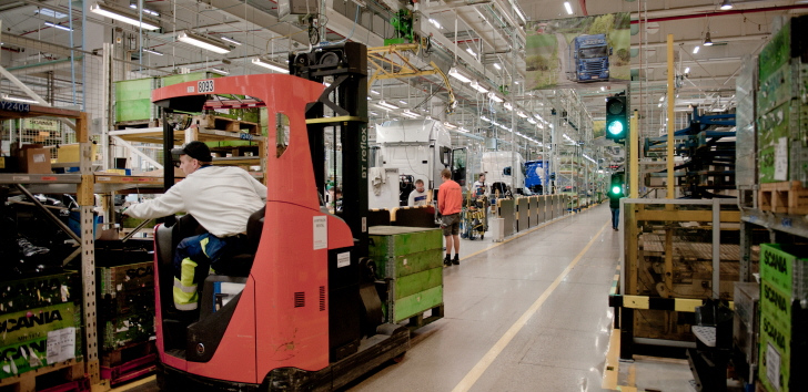 Tillverkningslokal för transport där en man sitter i en maskin med pall och har grönt ljus att köra på gången