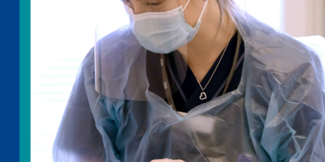 Bild på person på sjukhus iklädd munskydd, visir och skyddsförkläde. Personen håller i något som ser ut att vara en diabetespenna. 