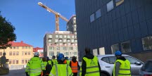 Ryggar på en grupp arbetsplatskontrollanter från olika myndigheter som inspekterar en byggarbetsplats.