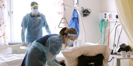 Bild på person på sjukhus iklädd munskydd, visir och skyddsförkläde. Personen håller i något som ser ut att vara en diabetespenna. 