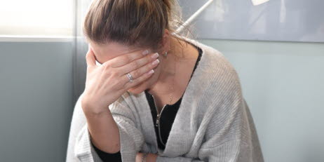 Trött kvinna som döljer sitt ansikte med ena handen