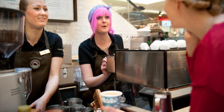 Bild på två unga kvinnor som arbetar på ett kafé.