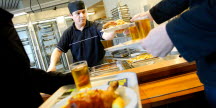 En man serverar mat till en kund som bär på en bricka