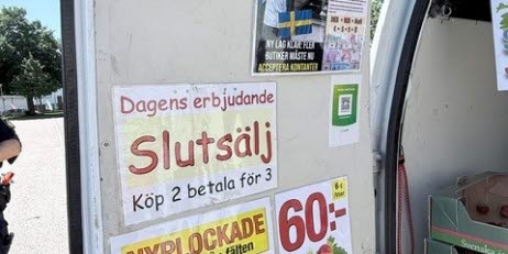 En skåpbil med skyltar som annonserar erbjudanden för svenska jordgubbar och information om priser.