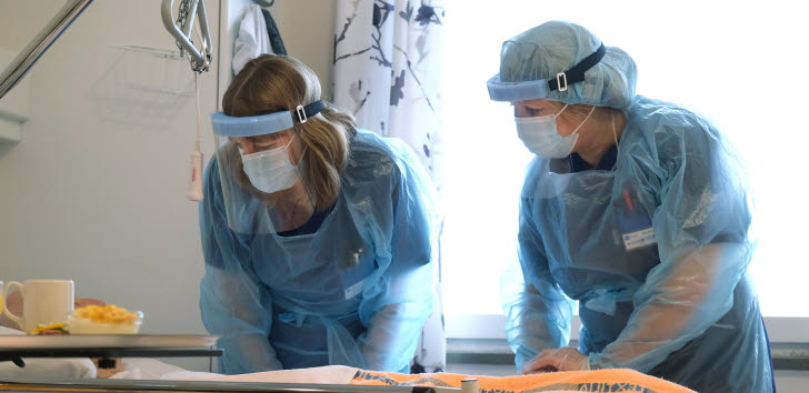 Två sjuksköterskor som vårdar en patient.