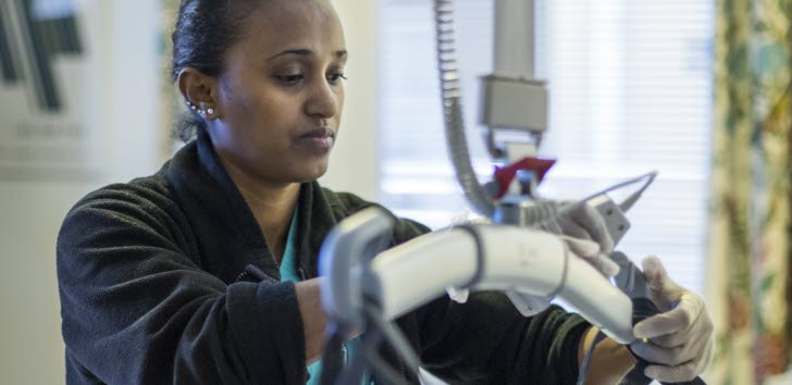 Person hanterar medicinsk utrustning i ett vårdrum.