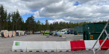 En grupp inspektörer och kontrollanter från flera olika myndigheter står på en byggarbetsplats med ett körhinder i betong i förgrunden.