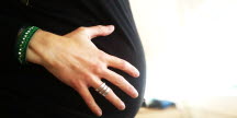 Bild på en låtsasgravid mans mage med kvinnlig hand på