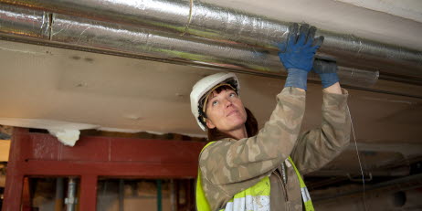 Bild från byggarbetsplats där byggjobbare isolerar rör