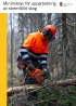 Foto. Omslagsbild som visar en man i skyddsutrustning och motorsåg som sågar av grenar på en liggande tall i skogen.