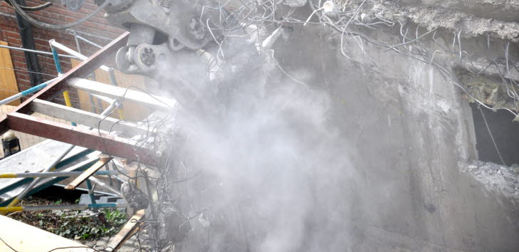 Byggarbetsplats där det rivs och skapar ett moln av stendamm.