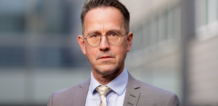 Person i kostym tittar in i kameran.