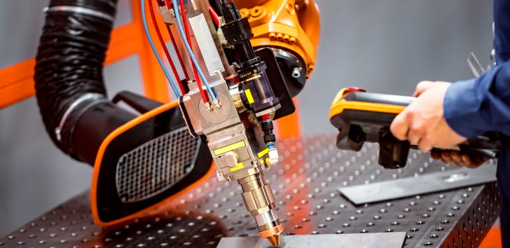 En industrirobotarm används för att utföra en teknikprocess på en metallplatta.