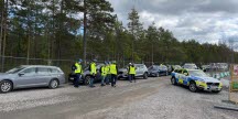 En polisbil står på en väg och flera personer iklädda varselvästar står i närheten