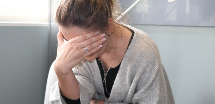 Trött kvinna som döljer sitt ansikte med ena handen