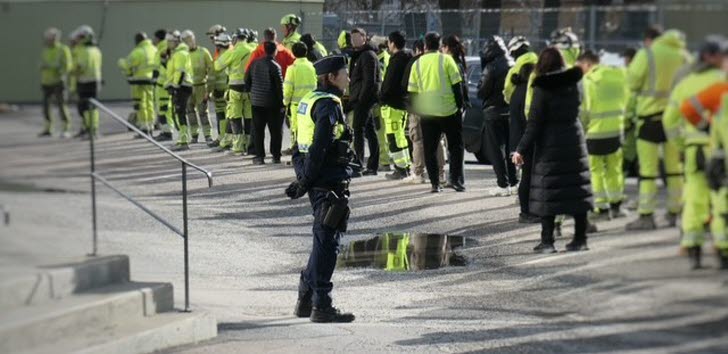 Ett stort antal arbetstagare med skyddsvästar på en byggarbetsplats under en myndighetsgemensam kontrollinsats.