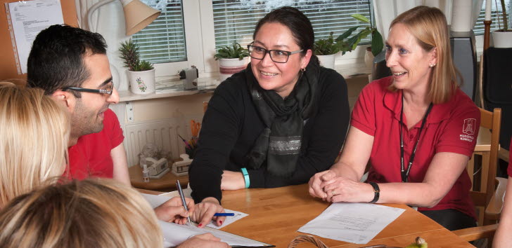 Bild på några medarbetare inom hemtjänsten som har ett möte vid ett bord.